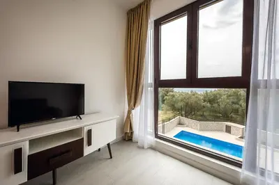 a living room with a tv and a large window at Adria lux apartmens 2 in Sveti Stefan
