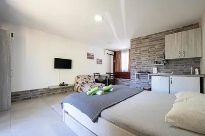 a bedroom with a large bed and a kitchen at Apartments Obala in Podgorica
