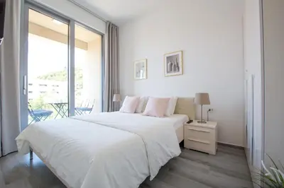 a white bedroom with a large bed and a window at Apart SKY Residence with sea view in DELMAR in Budva