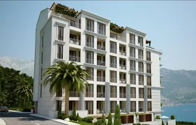 a white building with a palm tree in front of it at Apart SKY Residence with sea view in DELMAR in Budva
