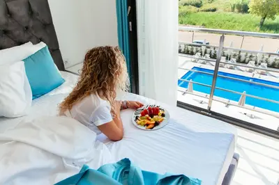 a little girl sitting on a bed with a plate of fruit at Hotel Ambiente Ulcinj in Ulcinj