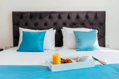 a tray of food and orange juice on a bed at Hotel Ambiente Ulcinj in Ulcinj