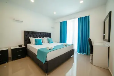 a bedroom with a large bed with blue pillows at Hotel Ambiente Ulcinj in Ulcinj