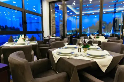 a dining room with tables and chairs and windows at Hotel Ambiente Ulcinj in Ulcinj