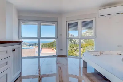 a white bedroom with large windows and a bed at Dolaca Villas in Sutomore