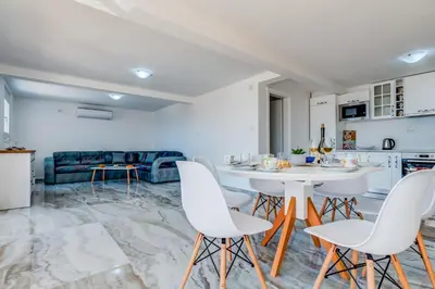 a kitchen and living room with a white table and chairs at Dolaca Villas in Sutomore