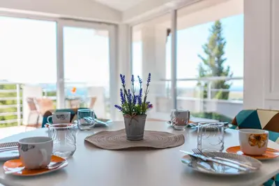 a table with plates and cups and a vase with purple flowers at Dolaca Villas in Sutomore