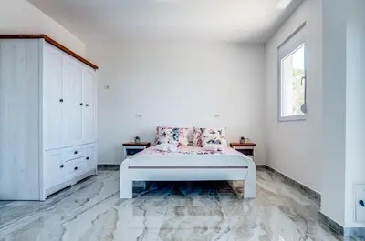 a white bedroom with a bed and a window at Dolaca Villas in Sutomore