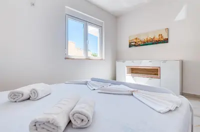 a white bedroom with towels on a bed at Dolaca Villas in Sutomore