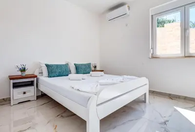a white bed in a white room with a window at Dolaca Villas in Sutomore