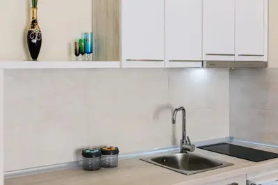 a kitchen with a sink and white cabinets at Apolon Apart in Bar, Susanj