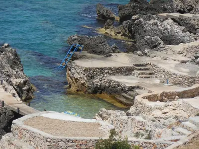 a blue ladder in the water next to the ocean at Apartments Harmony in Utjeha