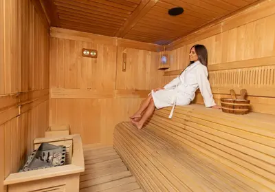 a woman sitting on the edge of a sauna at Hotel Aurel in Podgorica