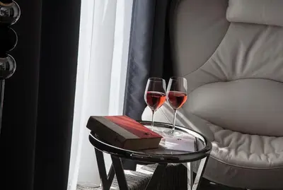 two glasses of wine on a table next to a chair at Hotel Aurel in Podgorica