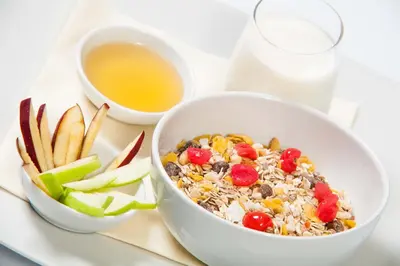 a bowl of cereal and a bowl of vegetables and a drink at Hotel Aurel in Podgorica