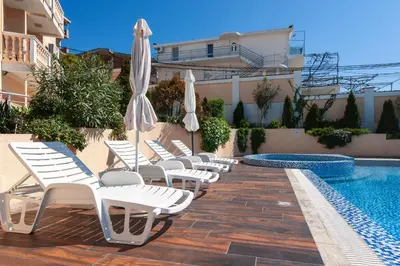 a row of chairs and umbrellas next to a swimming pool at Villa Orpheus in Bar