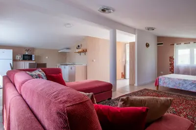 a living room with a red couch and a kitchen at Villa Orpheus in Bar