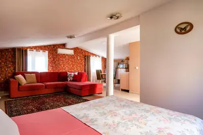a bedroom with a red couch and a living room at Villa Orpheus in Bar