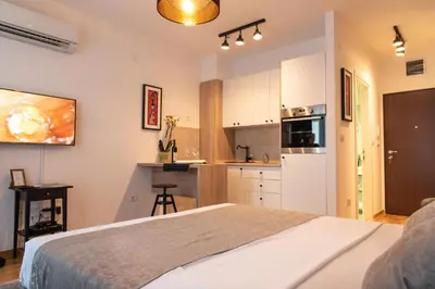 a bedroom with a large bed and a kitchen at Apartments Doclea in Podgorica