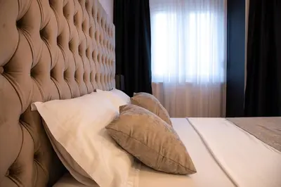 a bedroom with a bed with pillows and a window at Apartments Doclea in Podgorica