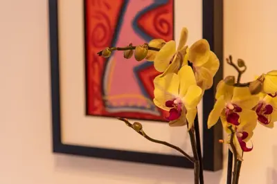 a vase with flowers in front of a painting at Apartments Doclea in Podgorica