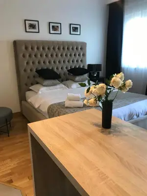 a bedroom with a bed with a vase of flowers on a table at Apartments Doclea in Podgorica