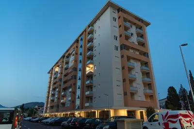 a tall building with cars parked in a parking lot at Apartments Doclea in Podgorica
