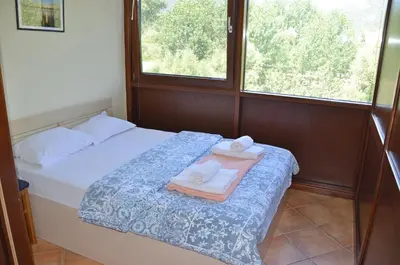 a bedroom with a bed with two towels and two windows at Hotel Pelikan in Virpazar