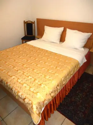 a large bed with a yellow blanket on it at Hotel Pelikan in Virpazar