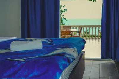 a bed with a blue comforter with a view of the ocean at Sun Apartments in Ulcinj