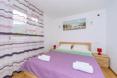 a bedroom with a purple bed with two white pillows at Apartments EcoNature in Virpazar