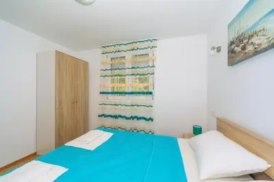 a bedroom with a blue bed and a window at Apartments EcoNature in Virpazar