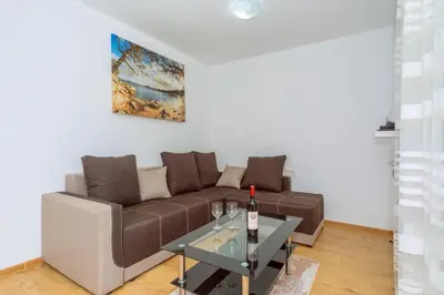 a living room with a brown couch and a table at Apartments EcoNature in Virpazar
