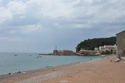 a beach with people laying on the sand and the water at Seaside Apartments Petrovac in Petrovac na Moru