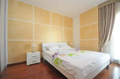 a bedroom with a white bed and a wooden floor at Seaside Apartments Petrovac in Petrovac na Moru