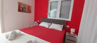 a red bedroom with a white bed and a red wall at Apartment Boki in Budva