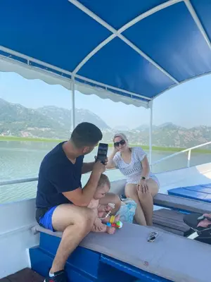 a man taking a picture of a baby on a boat at Skadar Lake Apartment-Nikola in Podgorica