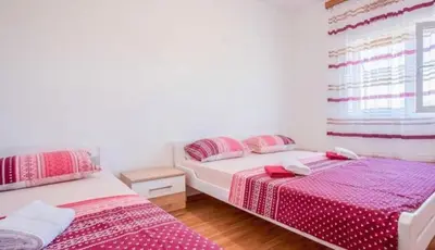 two beds in a bedroom with pink and white sheets at Skadar Lake Apartment-Nikola in Podgorica