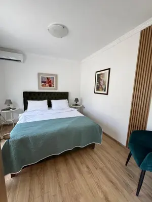 a bedroom with a large bed with a green blanket at Apartments Villa Marija in Petrovac na Moru