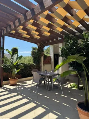 a patio with a table and chairs under a wooden pergola at Apartments Villa Marija in Petrovac na Moru