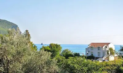 a house on a hill with the ocean in the background at Apartments Villa Marija in Petrovac na Moru