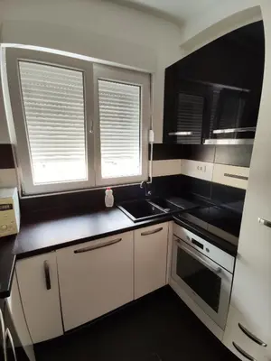 a kitchen with black and white appliances and two windows at Apartment For a Day in Podgorica