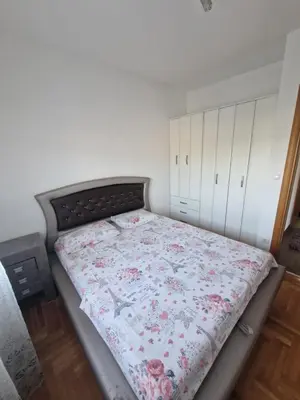 a bedroom with a bed with a floral quilt on it at Apartment For a Day in Podgorica