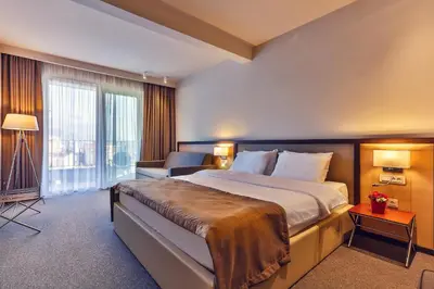 a hotel room with a large bed and a chair at Hotel Bono in Budva