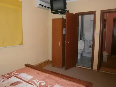 a bedroom with a bed and a tv and a bathroom at Vila Patria in Podgorica