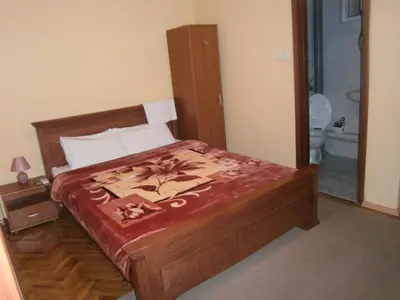 a bedroom with a wooden bed with a red blanket at Vila Patria in Podgorica