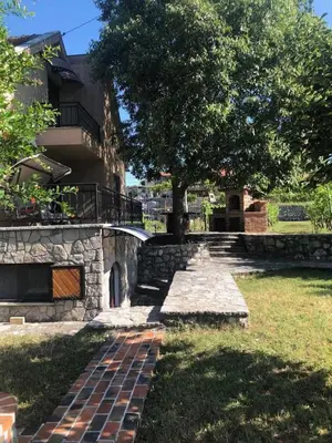a building with a tree and a brick walkway at T&A Apartment in Rijeka Crnojevića