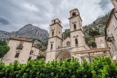an old building with two towers in front of a mountain at CENTRAL CATHEDRAL APARTMENT in Kotor