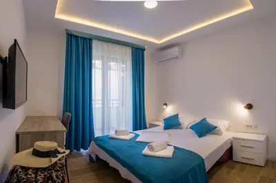 a bedroom with two beds and a window with blue curtains at Villa Marco Polo in Budva