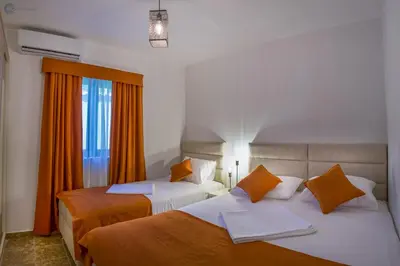 two beds in a hotel room with orange curtains at Villa Marco Polo in Budva